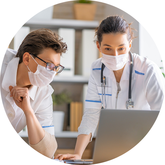 Two healthcare professionals, wearing masks, are collaborating while looking at a laptop. Keywords: nextgenu.